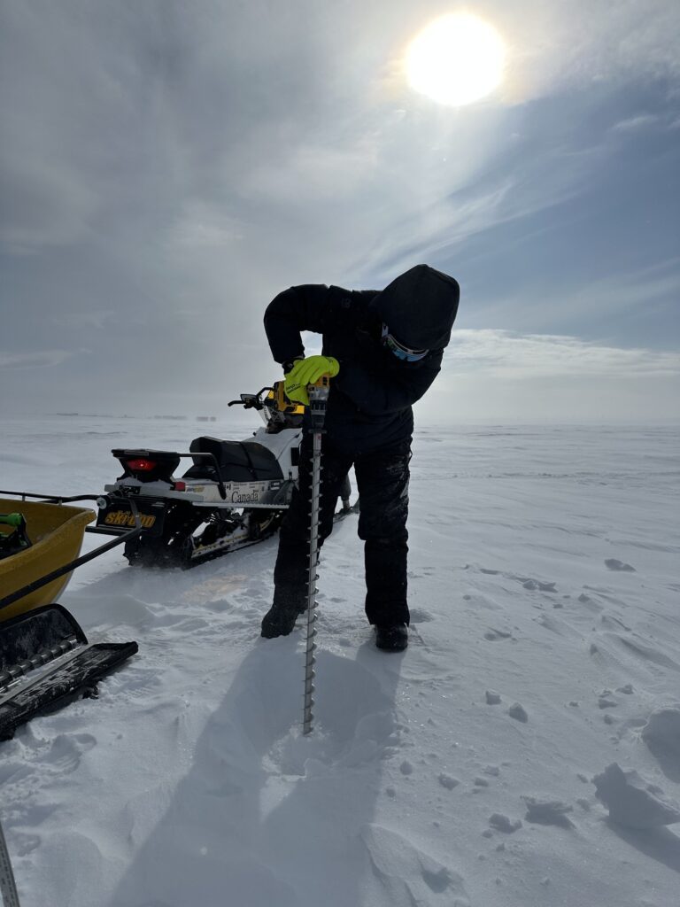 Researcher drilling into ice in the arctic